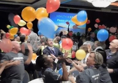 A group of people with balloons in the air.