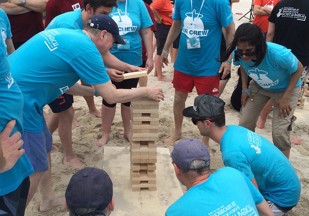A group of people playing a game of jenga on the beach.