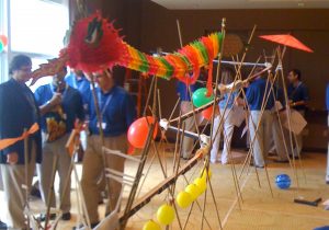 A group of people standing in a room with a bunch of sticks and balloons.