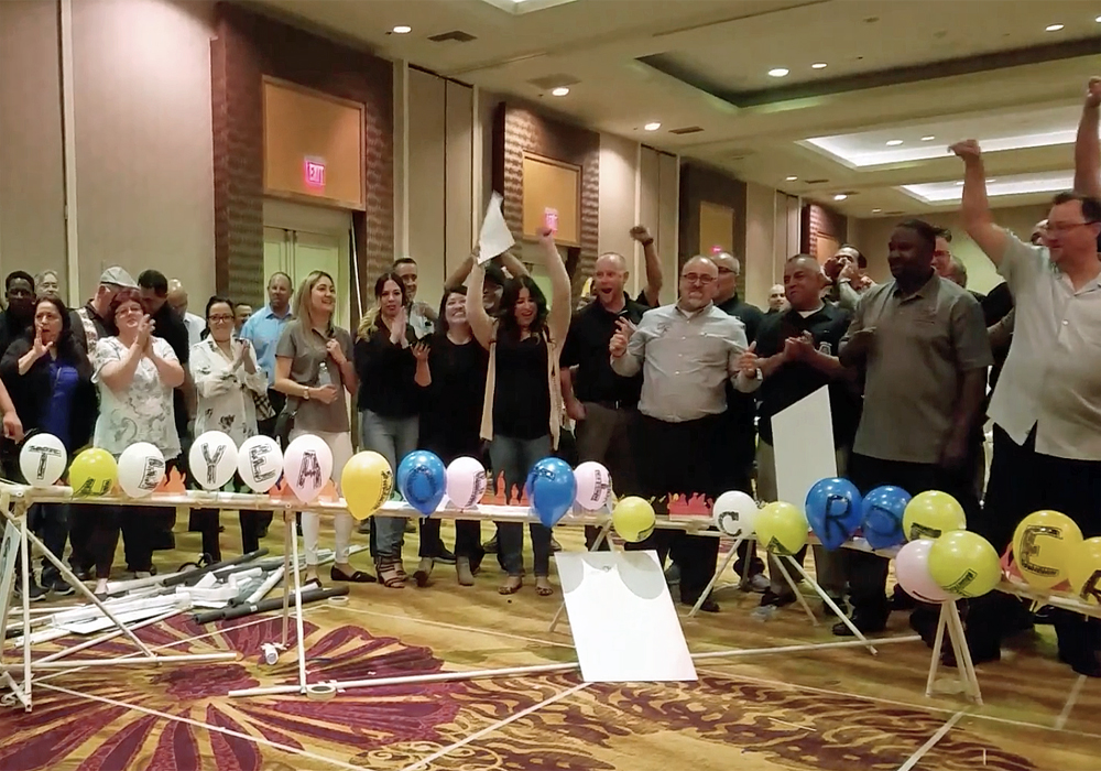 A group of people standing in a room with balloons.