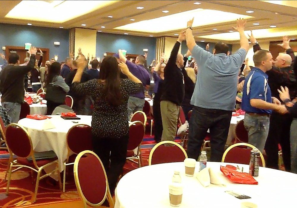 A group of people raising their hands in the air.