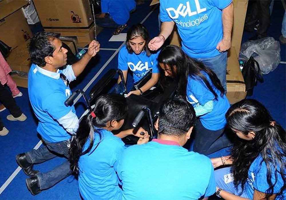 A group of people in blue t - shirts sitting on the floor.
