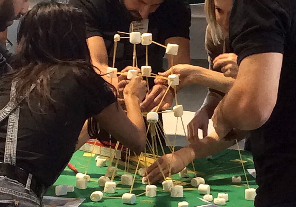 A group of people working on a tower of marshmallows.