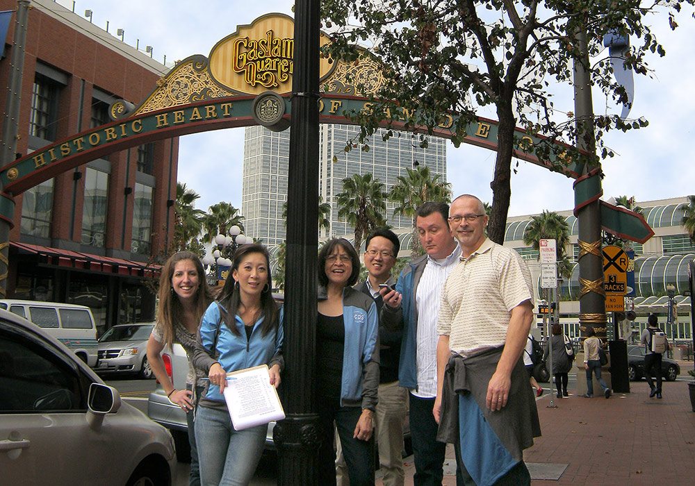 A group of people standing in front of a street sign.