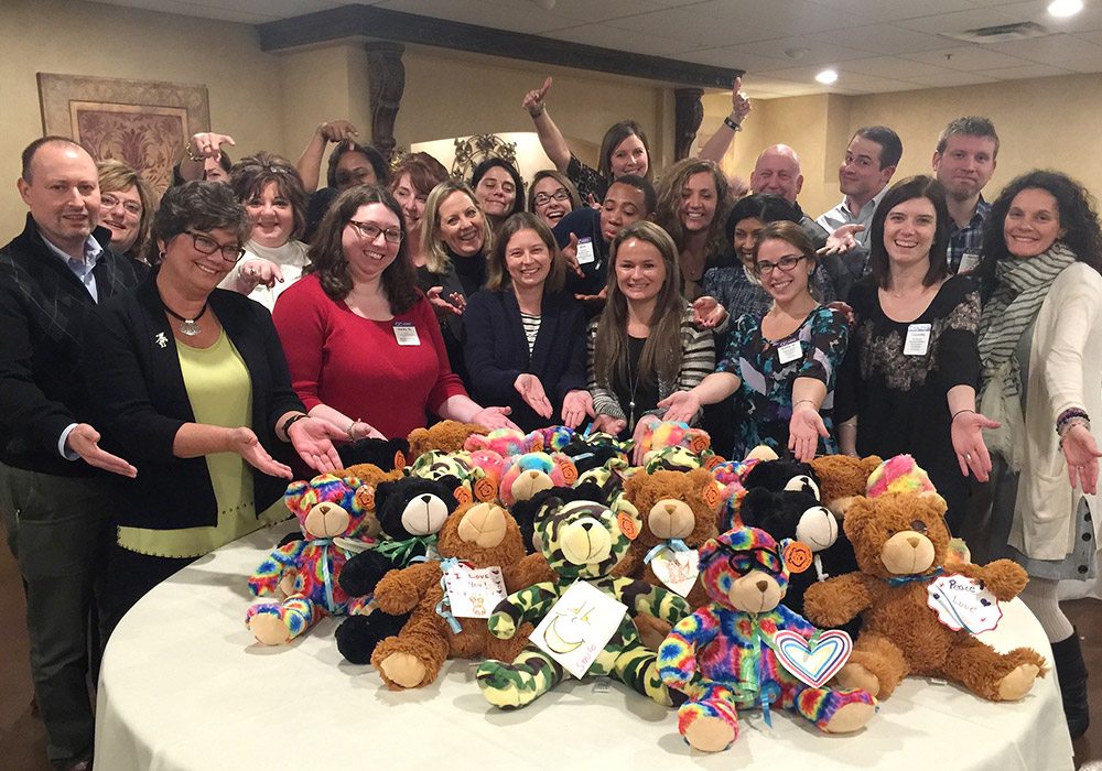 A group of people posing in front of a table full of teddy bears.