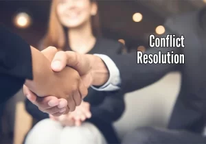 Two business people shaking hands with the words conflict resolution.