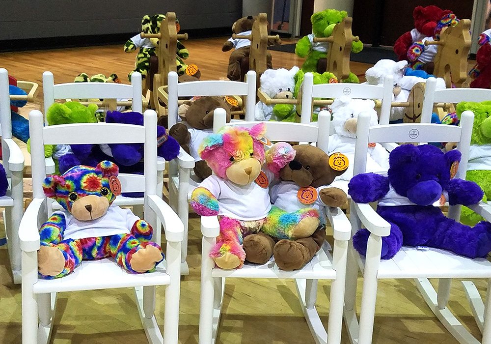 A group of teddy bears sitting in chairs.