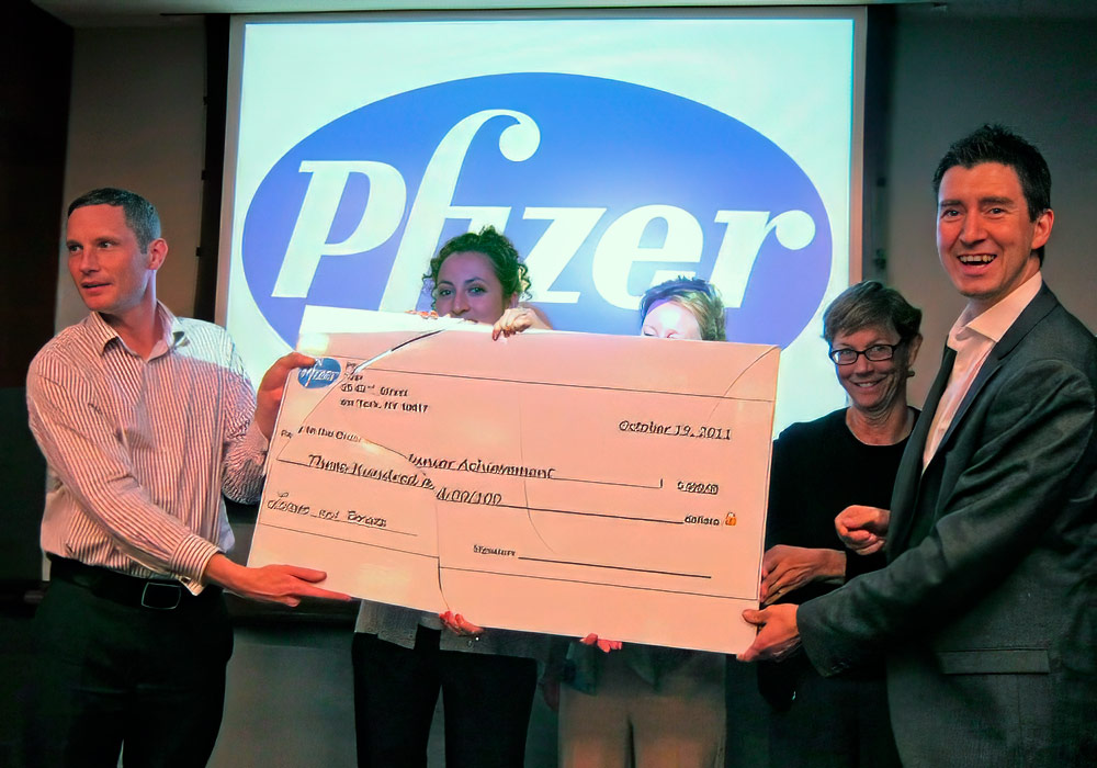 A group of people holding a check for pfizer.