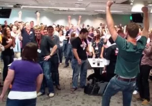 A group of people are dancing in a conference room.