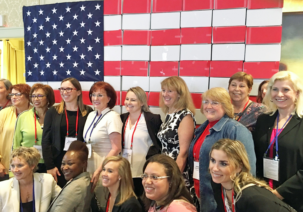 A group of women posing in front of an american flag.