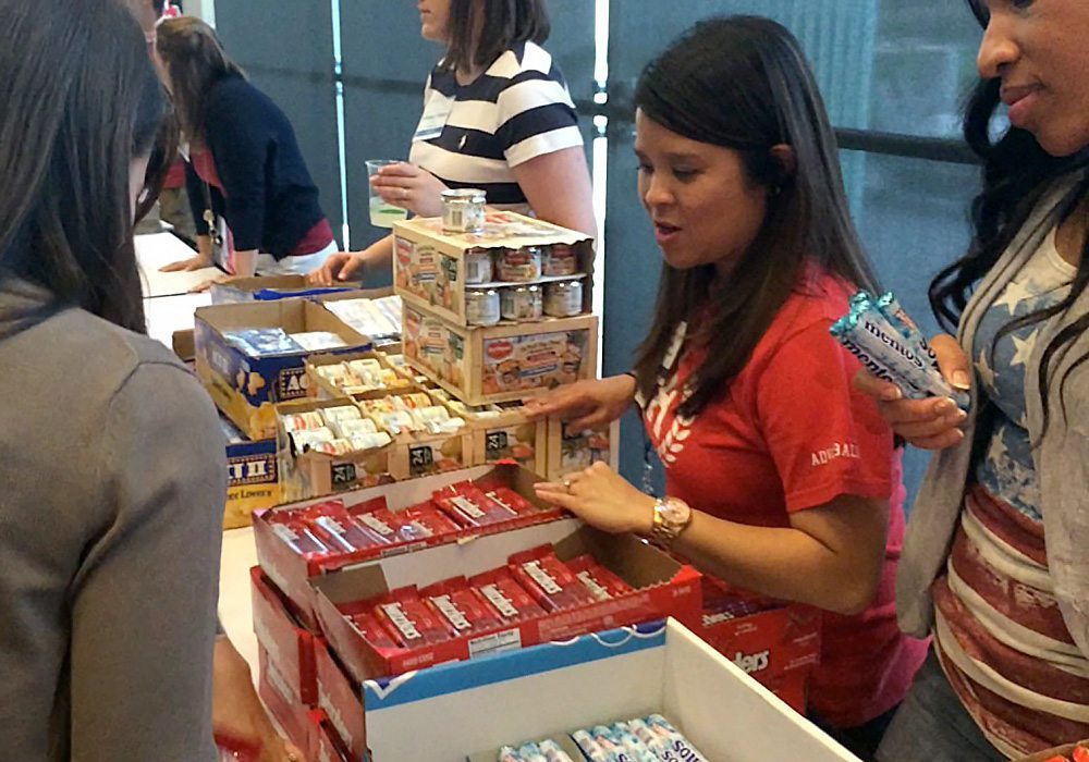 A group of people standing around a table with boxes of candy.