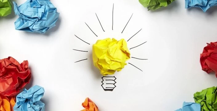A light bulb surrounded by colored crumpled paper.