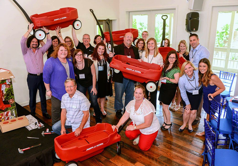 A group of people posing with red wagons.