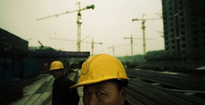 Two men in hard hats standing in front of a construction site.