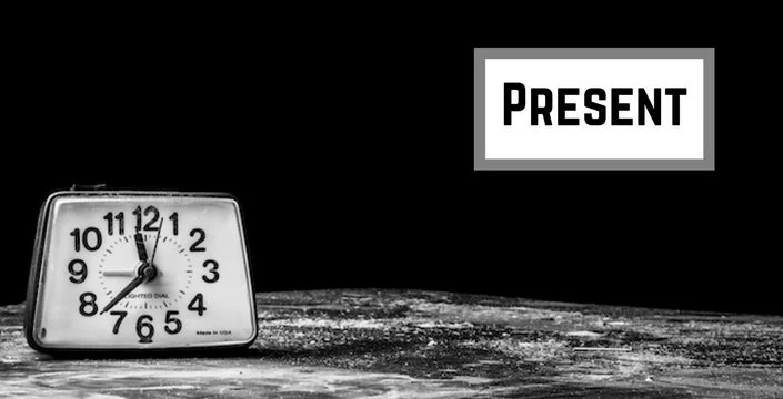 A black and white photo of a clock with the words present.