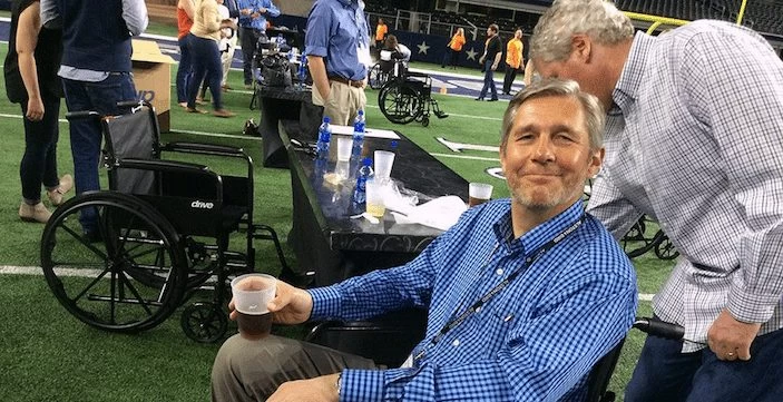 A wheelchair user enjoying a beer at a football game.