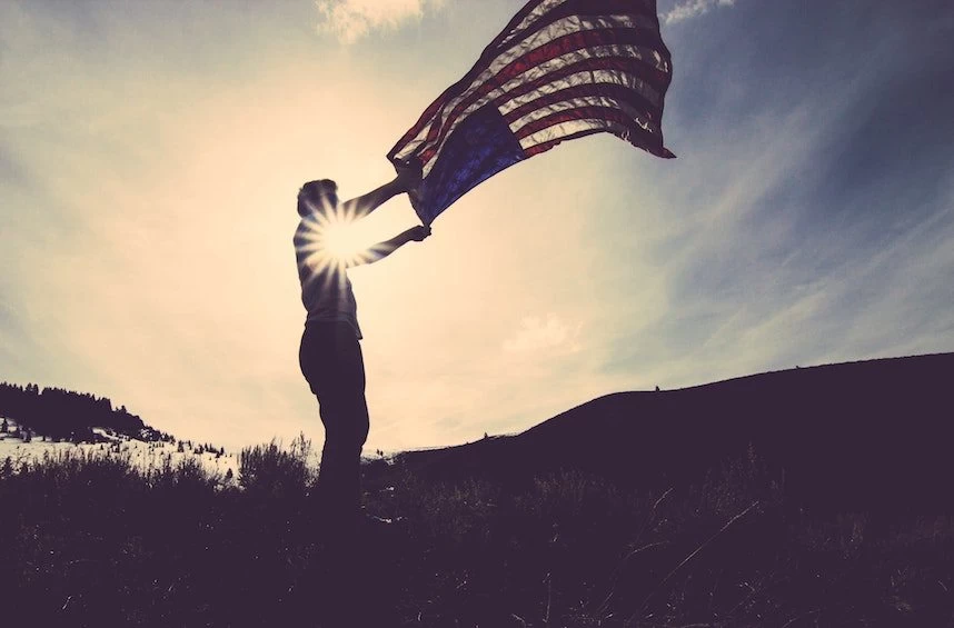 A silhouette of a man holding an american flag.