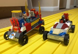 Two lego cars on a yellow surface.