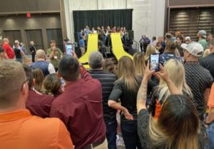 A crowd of people standing in front of a yellow slide.