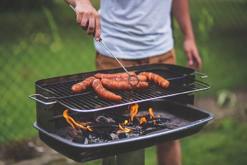 A man is grilling sausages on a grill.