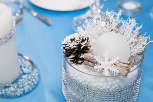 A table with candles and snowflakes on a blue tablecloth.