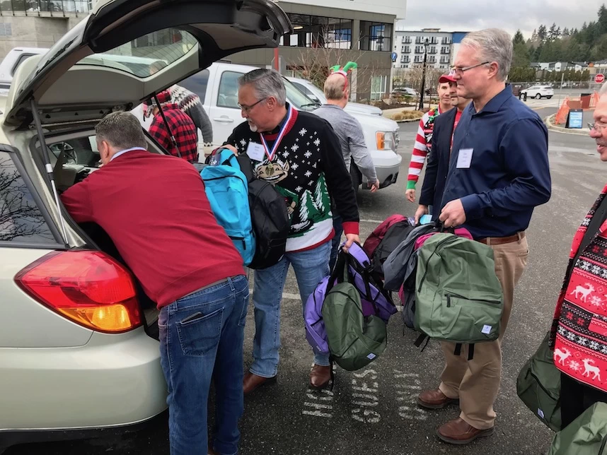 A group of people with backpacks in the trunk of a car.