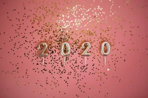 Confetti with the number 2020 on a pink background.