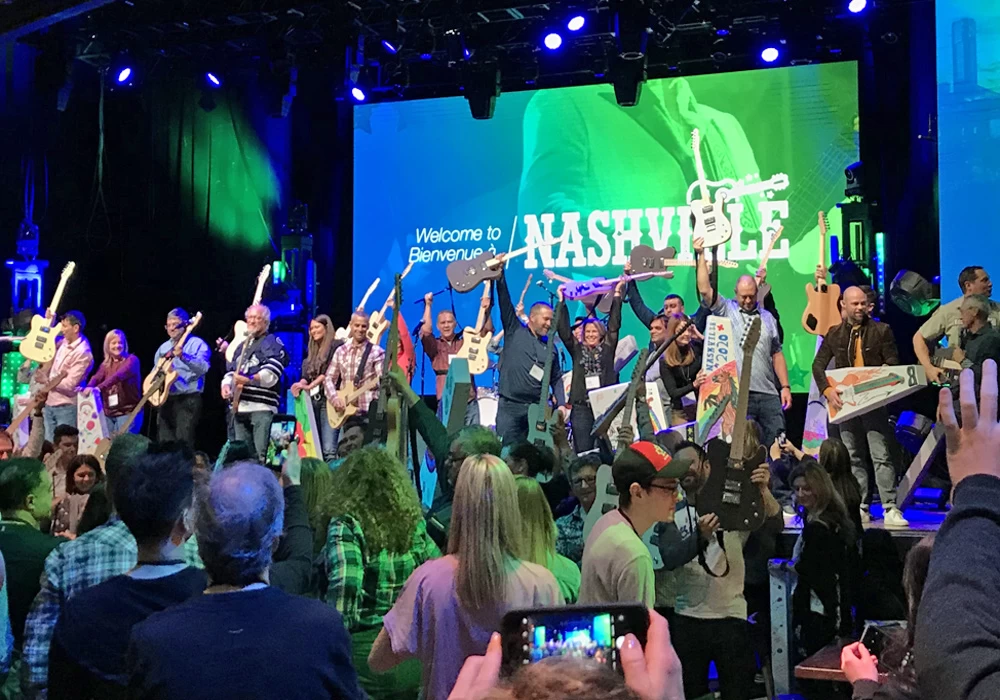 A group of people standing on stage expressing their appreciation in front of a green screen.