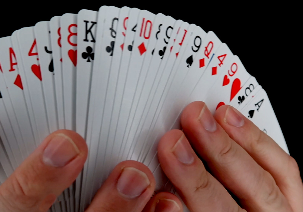 A pair of hands holding a deck of playing cards.