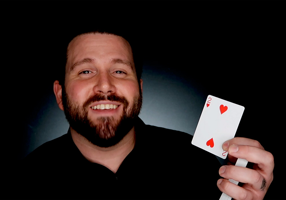 A man with a beard holding up a deck of cards.