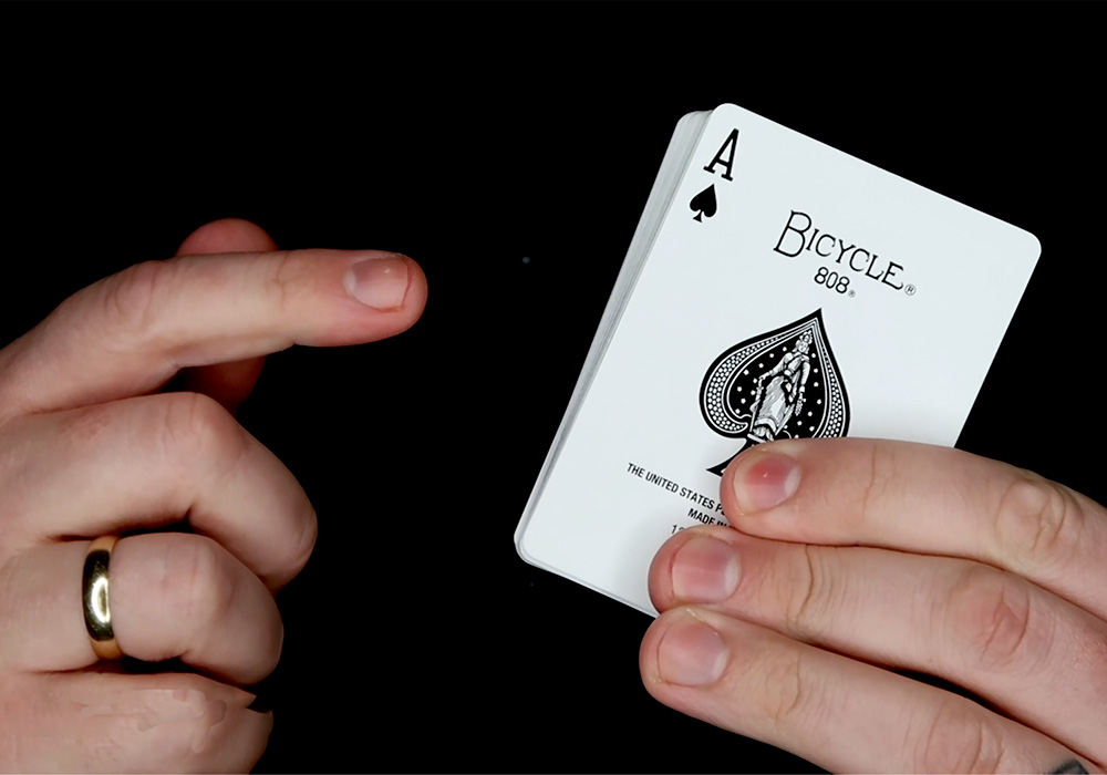 A person's hand holding an ace of spades.