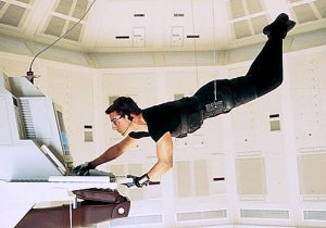 A man is hanging from a ceiling while using a computer.