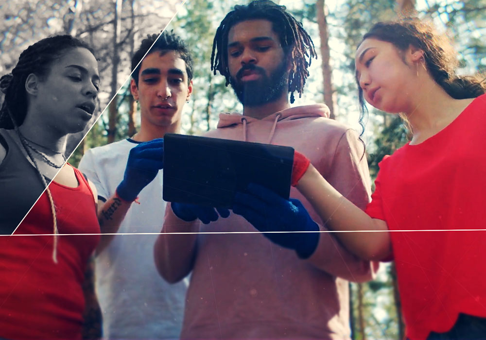 A group of people looking at a tablet in the woods.
