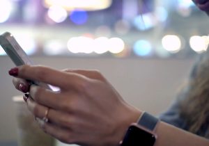 A woman is using a cell phone in a coffee shop.