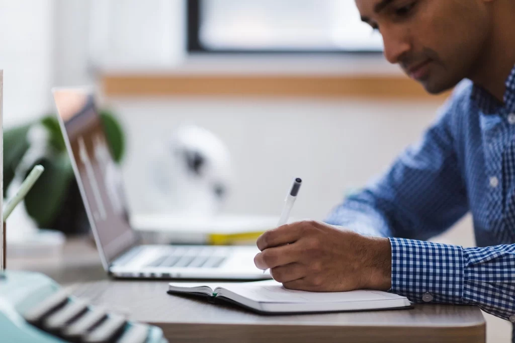 A man writing in a notebook at his desk.