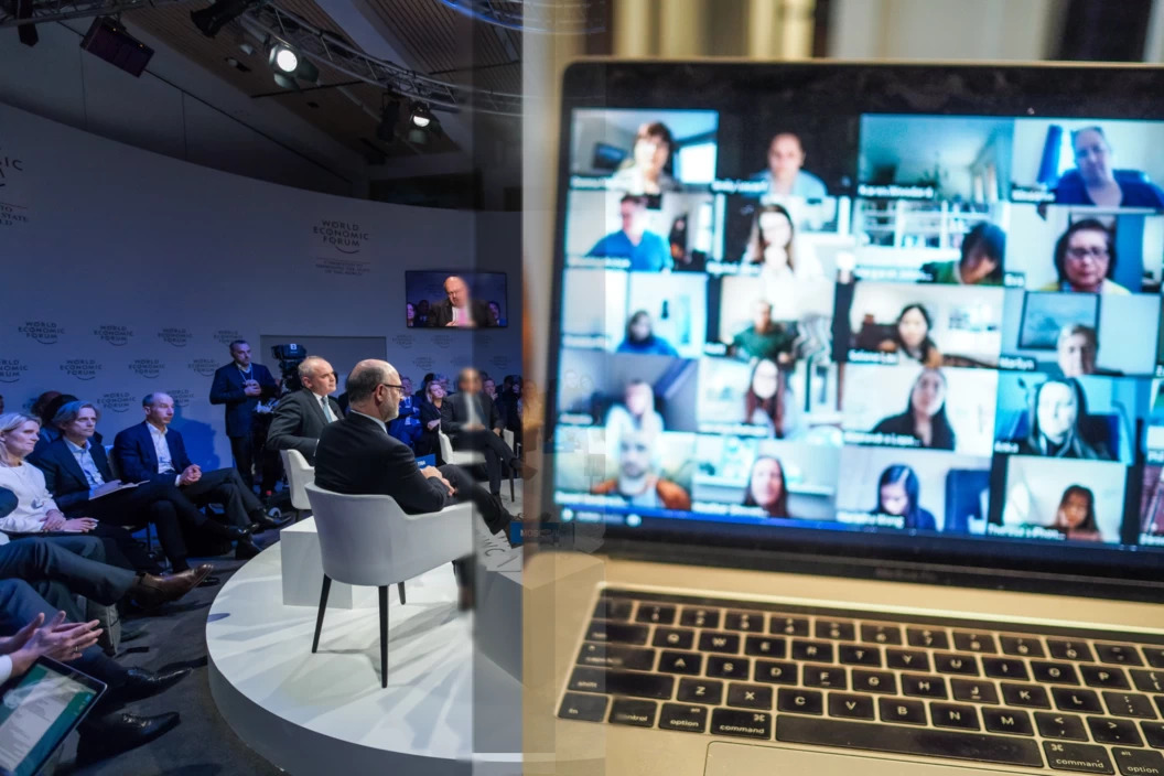 A laptop screen displaying a hybrid event with a group of people on a conference call.