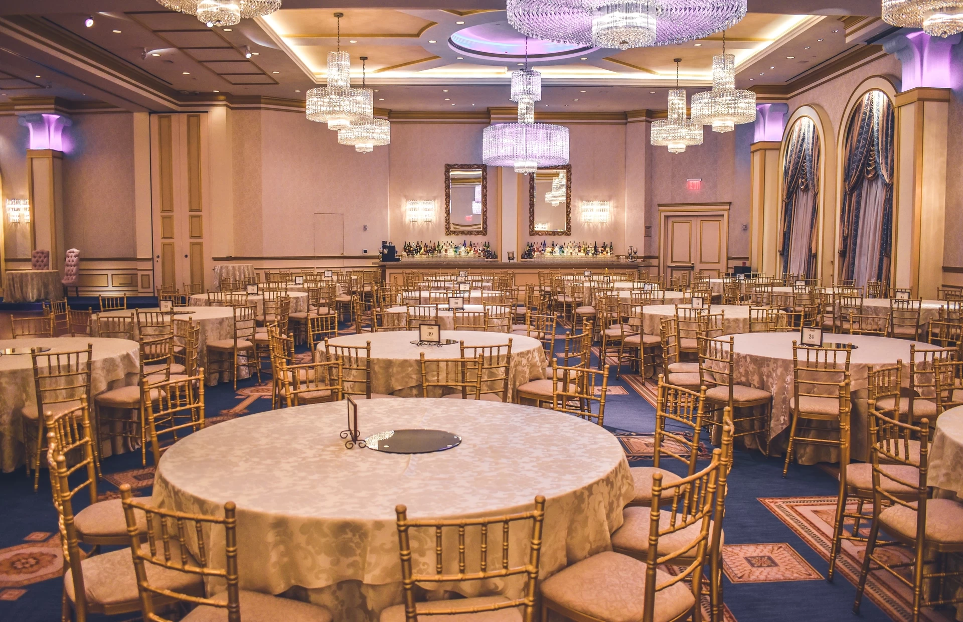 A spacious team building venue with tables and chairs arranged in a large ballroom.
