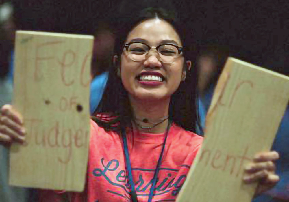 A woman holding up a sign that says fee or judge''.