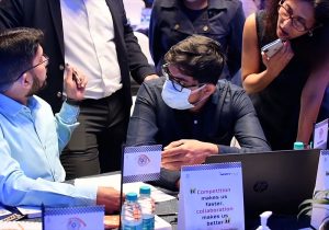 A group of people standing around a table with laptops.
