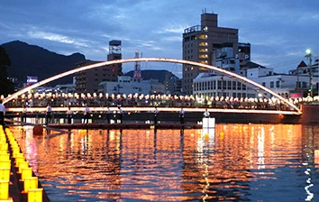 A bridge over a river with lit up lanterns.
