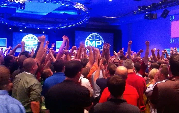 A crowd of people raising their hands in the air at a conference.