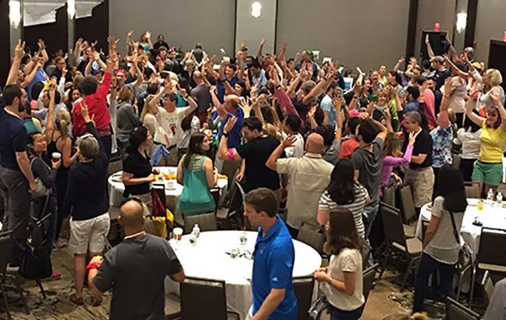 A large group of people in a room raising their hands.
