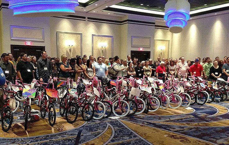 A group of people standing in front of a room full of bicycles.