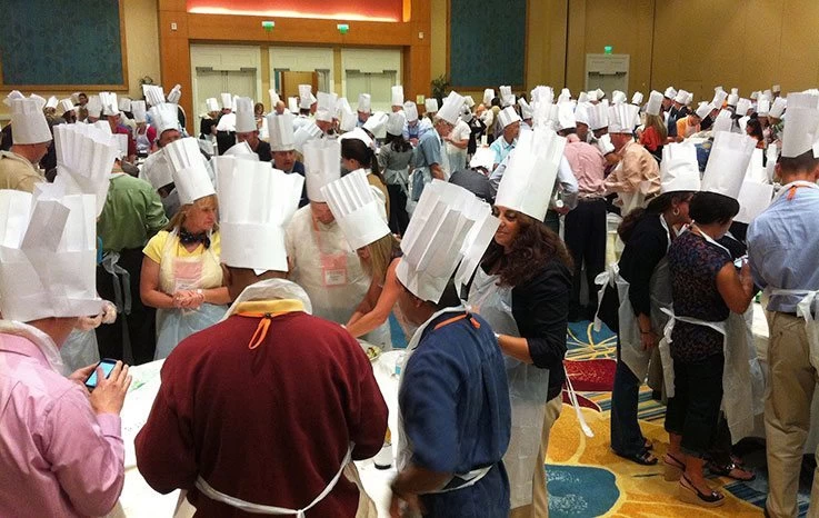 A large group of people in chef hats at a convention.