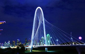 The dallas skyline at night with the bridge lit up.