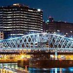 A city at night with a bridge over a river.