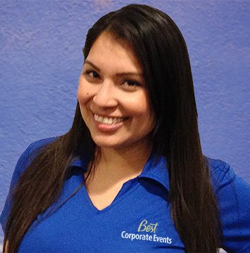 A woman in a blue shirt smiling in front of a blue wall.