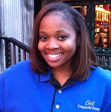 A young woman in a blue shirt standing in front of a restaurant.