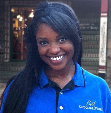 A woman in a blue polo smiles in front of a store.