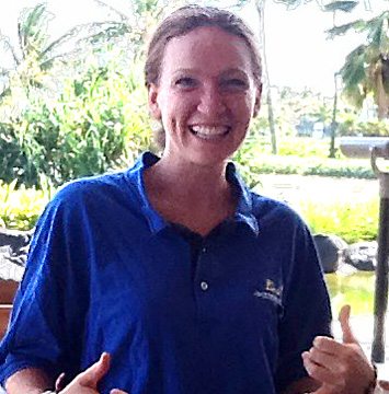 A woman in a blue shirt giving a thumbs up.